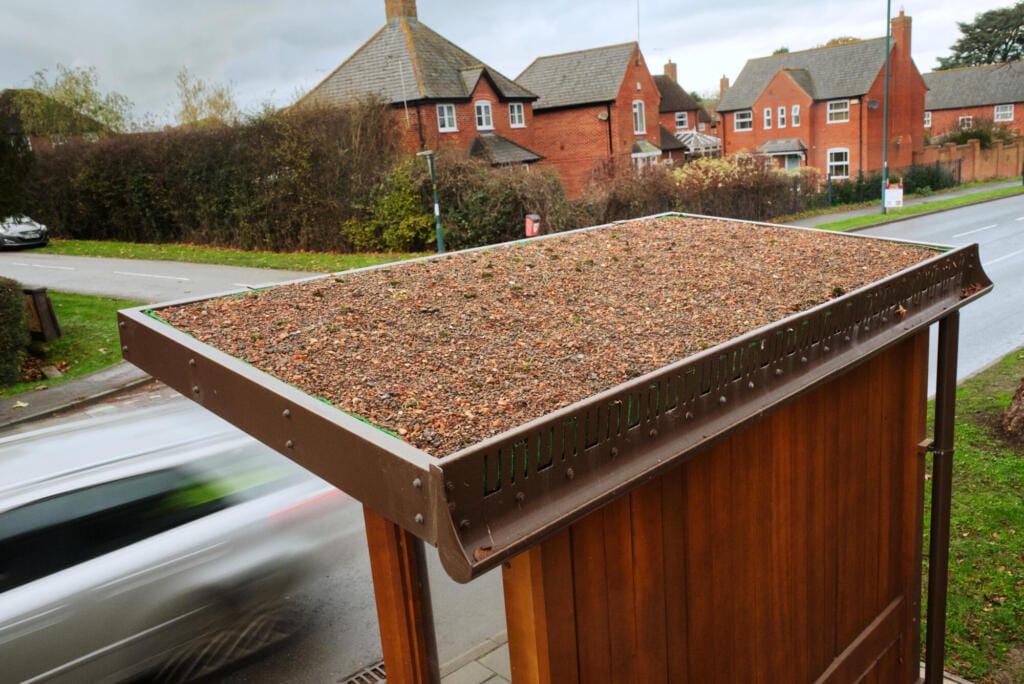 A newly installed green roof shelter with houses in the background.